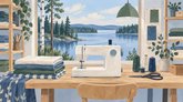 Ompelimon puupöydällä on valkoinen ompelukone, taiteltuja kankaita, lankarullia ja sakset. Hyllyillä on lisää kankaita, ja seinällä riippuu kaksi kangasnäytettä. Ikkunasta näkyy järvi ja metsää.
