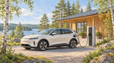 Valoisa kuvitus sähköauton latausasemasta Suomessa. Vaalea henkilöauto on kytketty latauslaitteeseen puurakennuksen vieressä.
